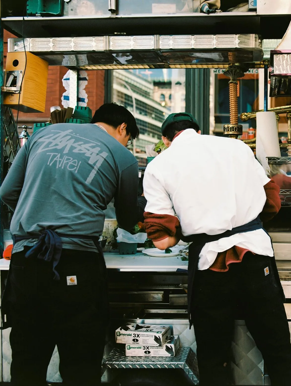 Two hospitality workers preparing food together in a kitchen