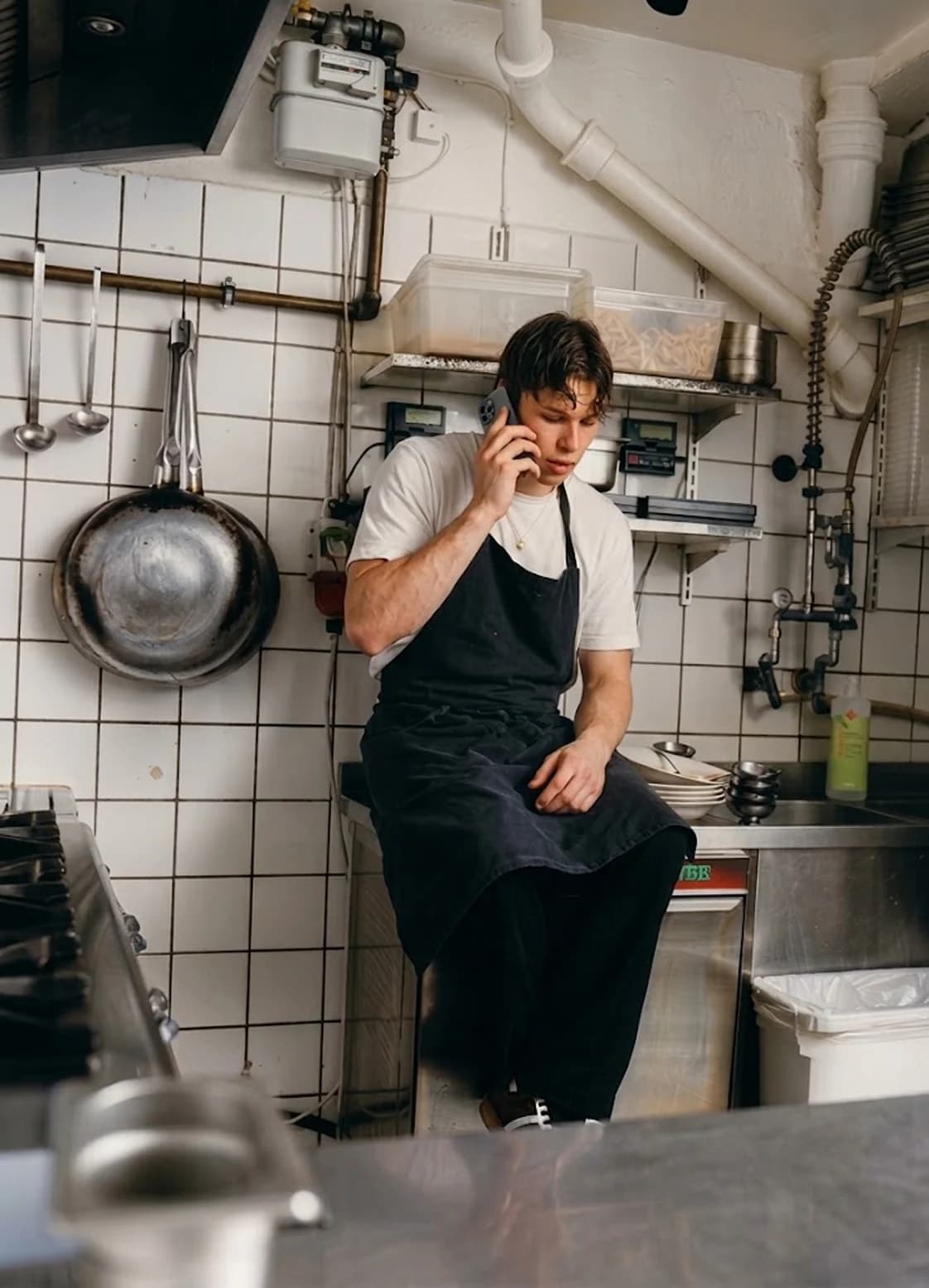 A hospitality worker handling a phone call in the kitchen