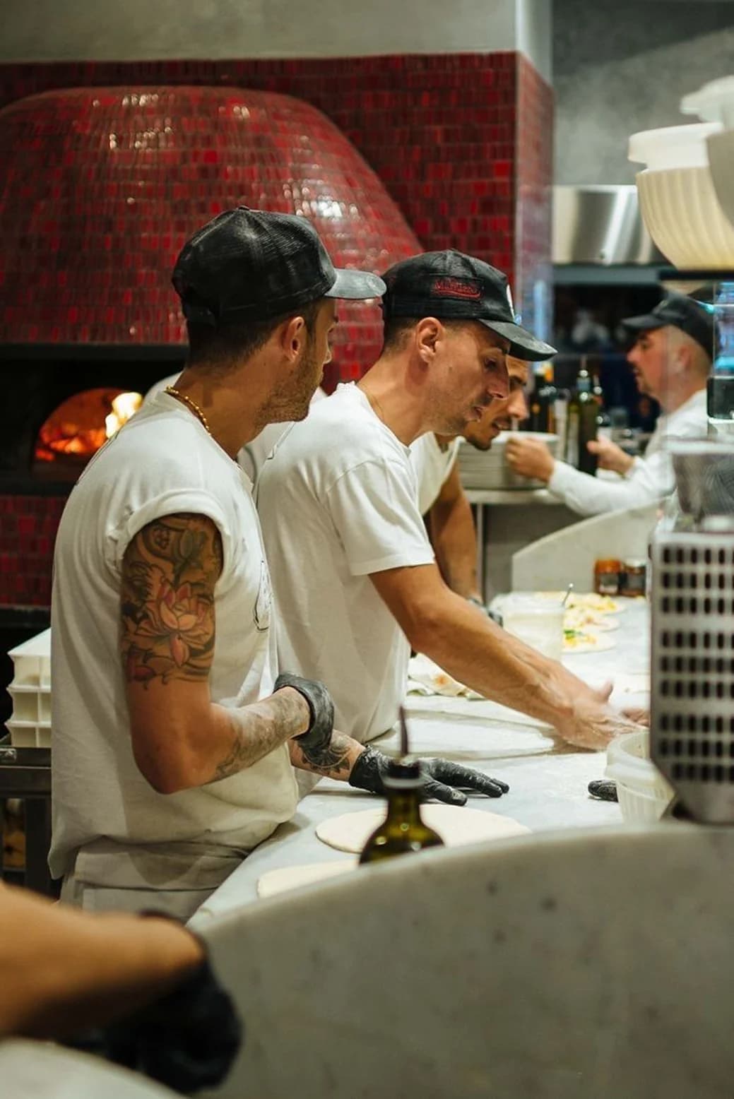 A kitchen team preparing pizzas during service